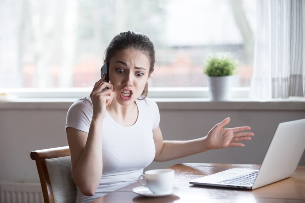 Upset woman engaged in a heated phone conversation, facing issues with debt collector.